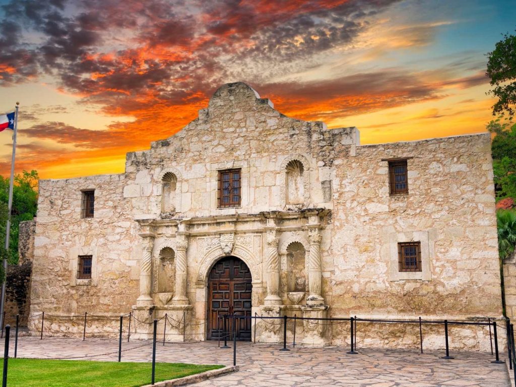 the alamo with the sun setting behind it