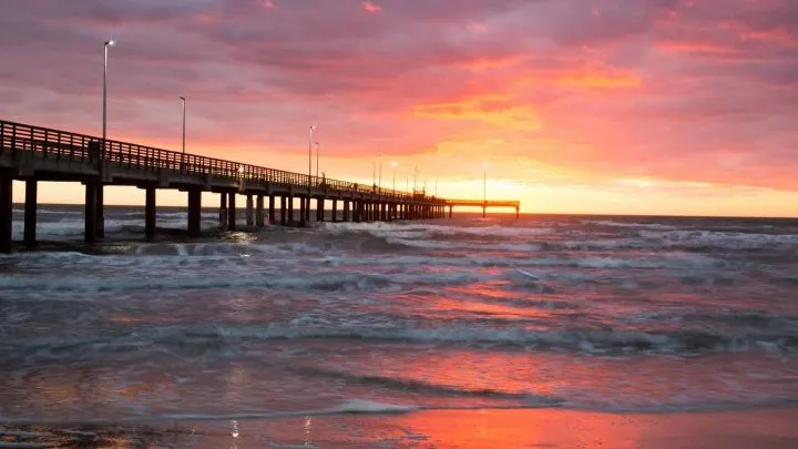 sunset over the ocean with a pier